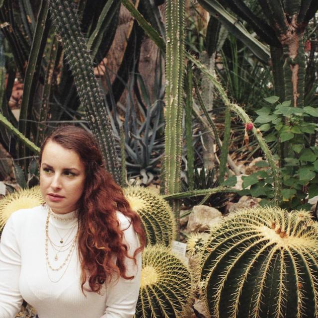 Dívka s výrazným náhrdelníkem v botanické zahradě s obřími kaktusy